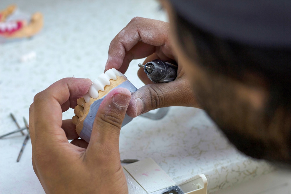 Dental technician shaping a set of dentures