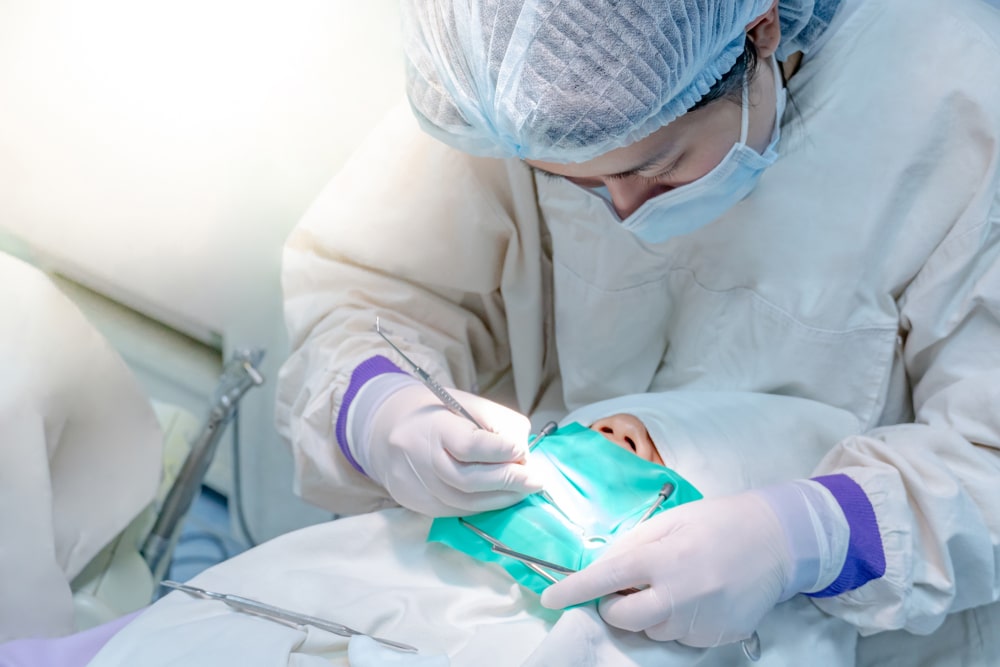 Dentist in protective gear treating a patient